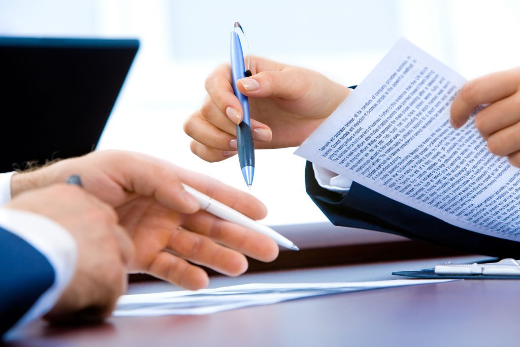 close up view of two people signing on a piece of paper