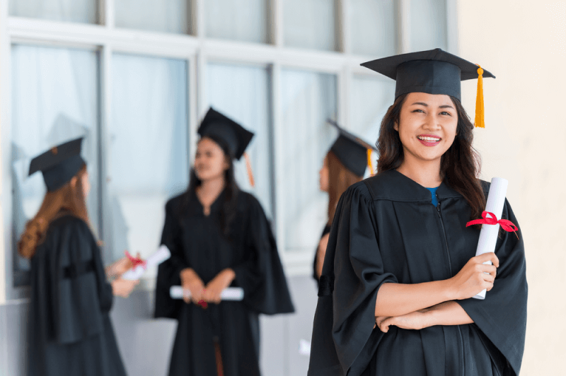 young woman in graduation attire holding her diploma