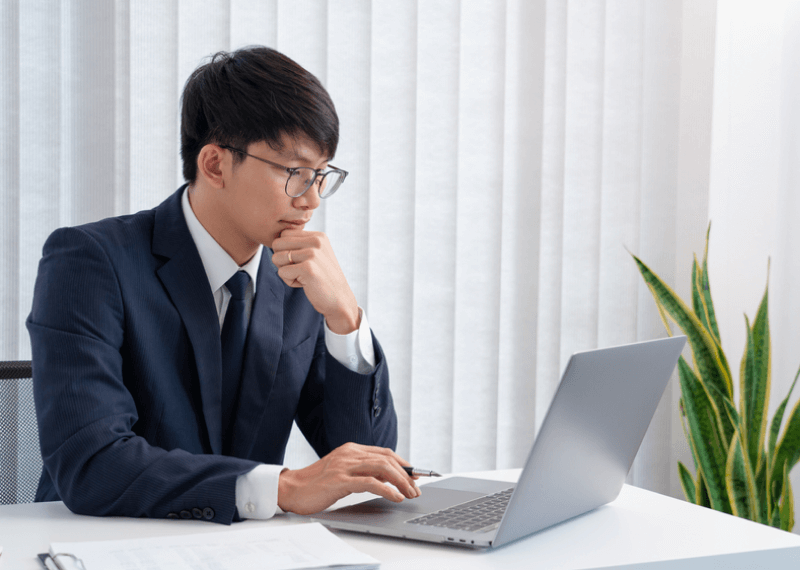 young man in corporate attire looking at his laptop