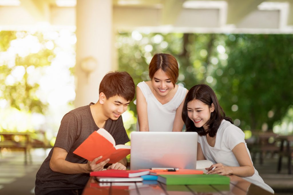 three students looking at a laptop